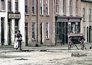 A Victorian image of a woman fetching water from a street pump in Church Street, Warrenpoint. This image has been fully restored, colourised and HD enhanced.