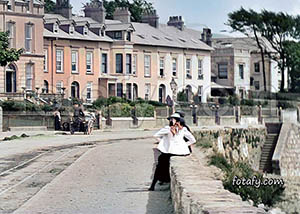 Old Warrenpoint image that has been restored and colourised of two ladies sitting on the seafront wall enjoying the sunshine