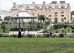 An old image that has been fully restored, HD enhanced and colourised of a woman pushing a pram in Warrenpoint park.