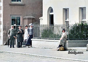 An old image of people enjoying the sea air outside a terraced house on the promenade in Warrenpoint. This image has been fully restored and colourised.