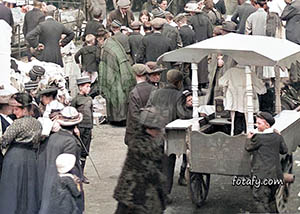 An old image of a young boy transfixed by a market stall. The image has been fully restored, colourised and HD enhanced.